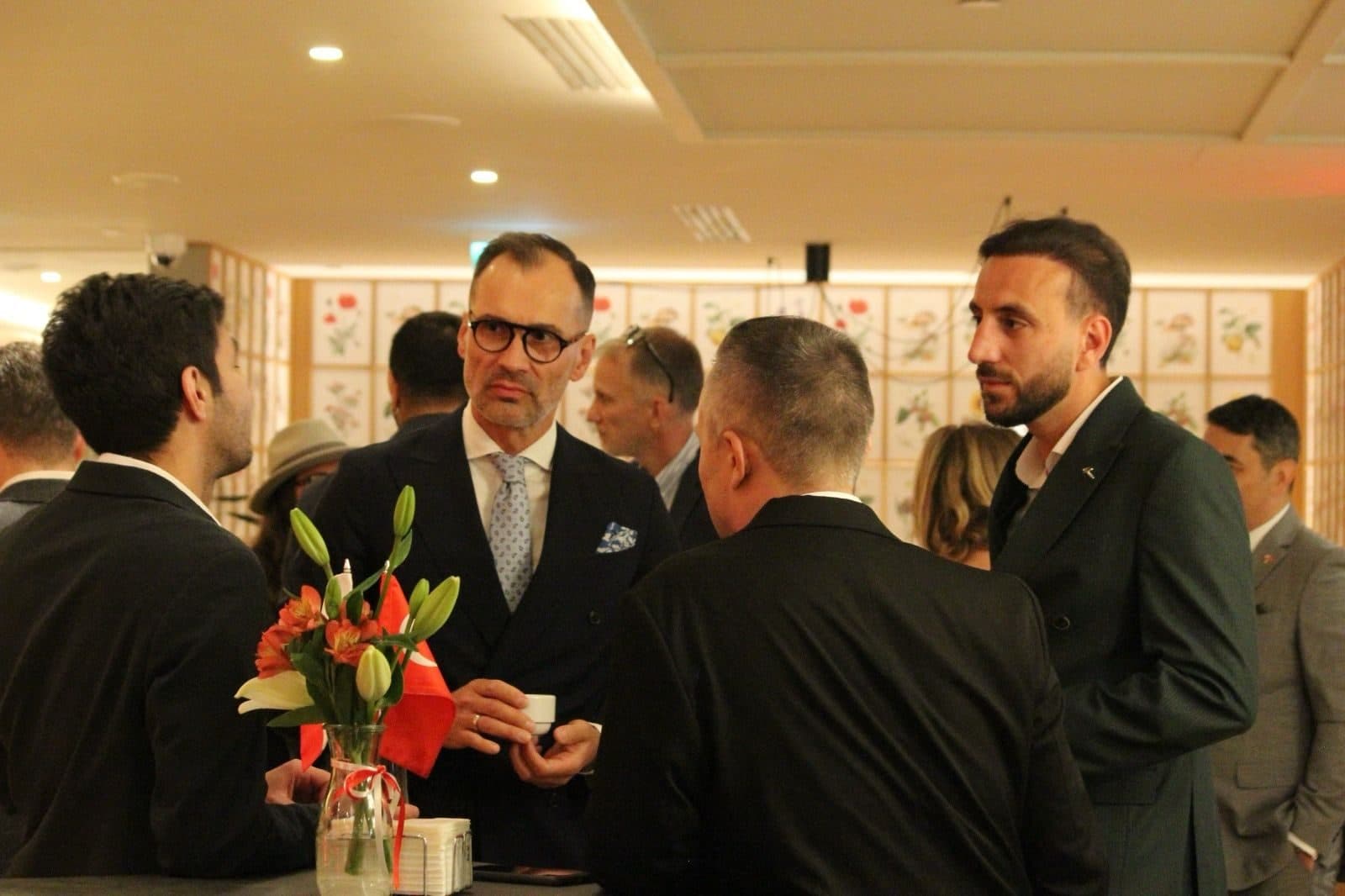 Guests talking around a table decorated with flowers and a small Turkish flag